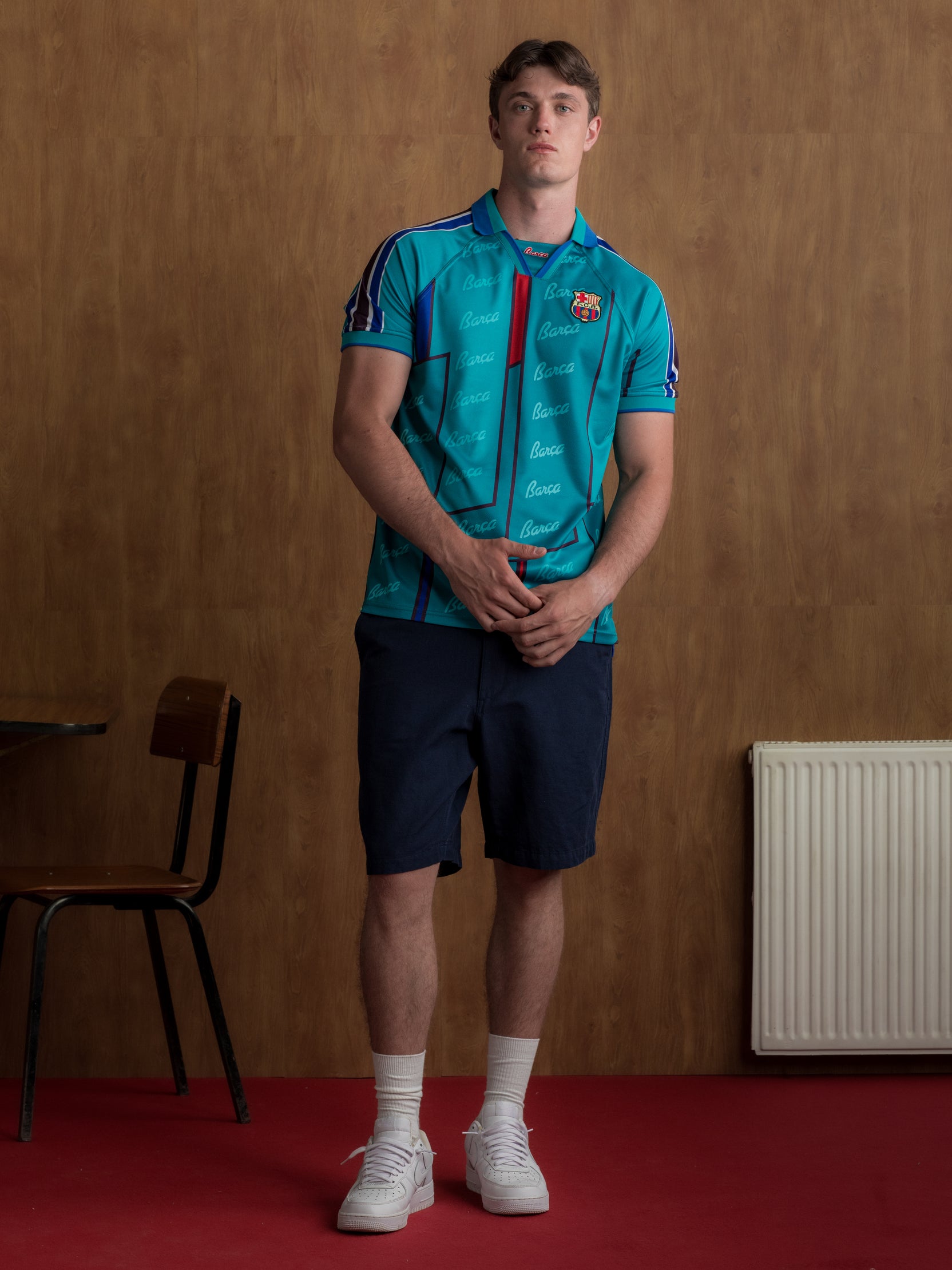 Teal short-sleeve polo shirt with FC Barcelona crest, blue and red accents, and Barça-themed script print.