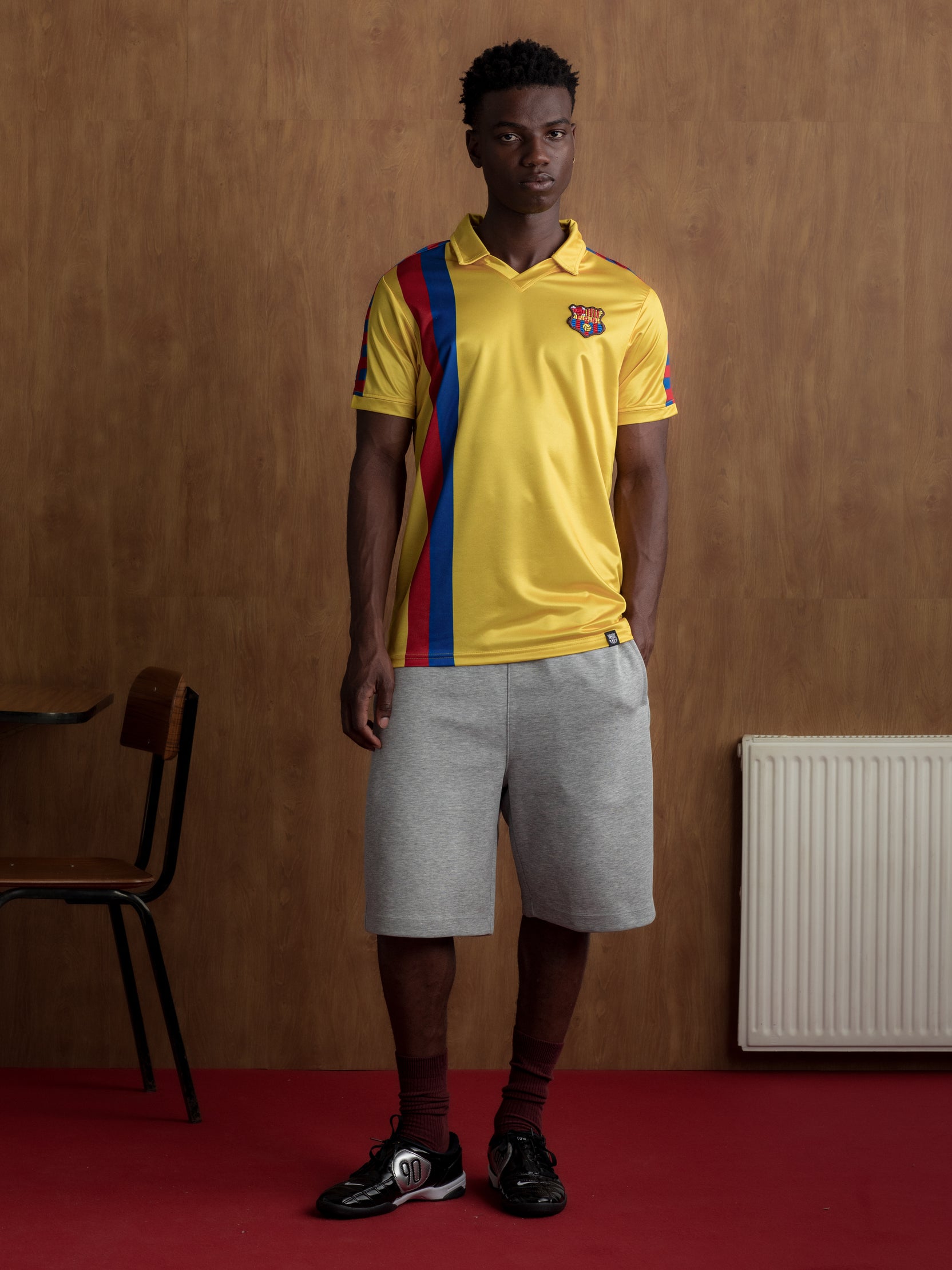Yellow short-sleeve polo shirt with FC Barcelona crest and vertical red and blue stripe design.