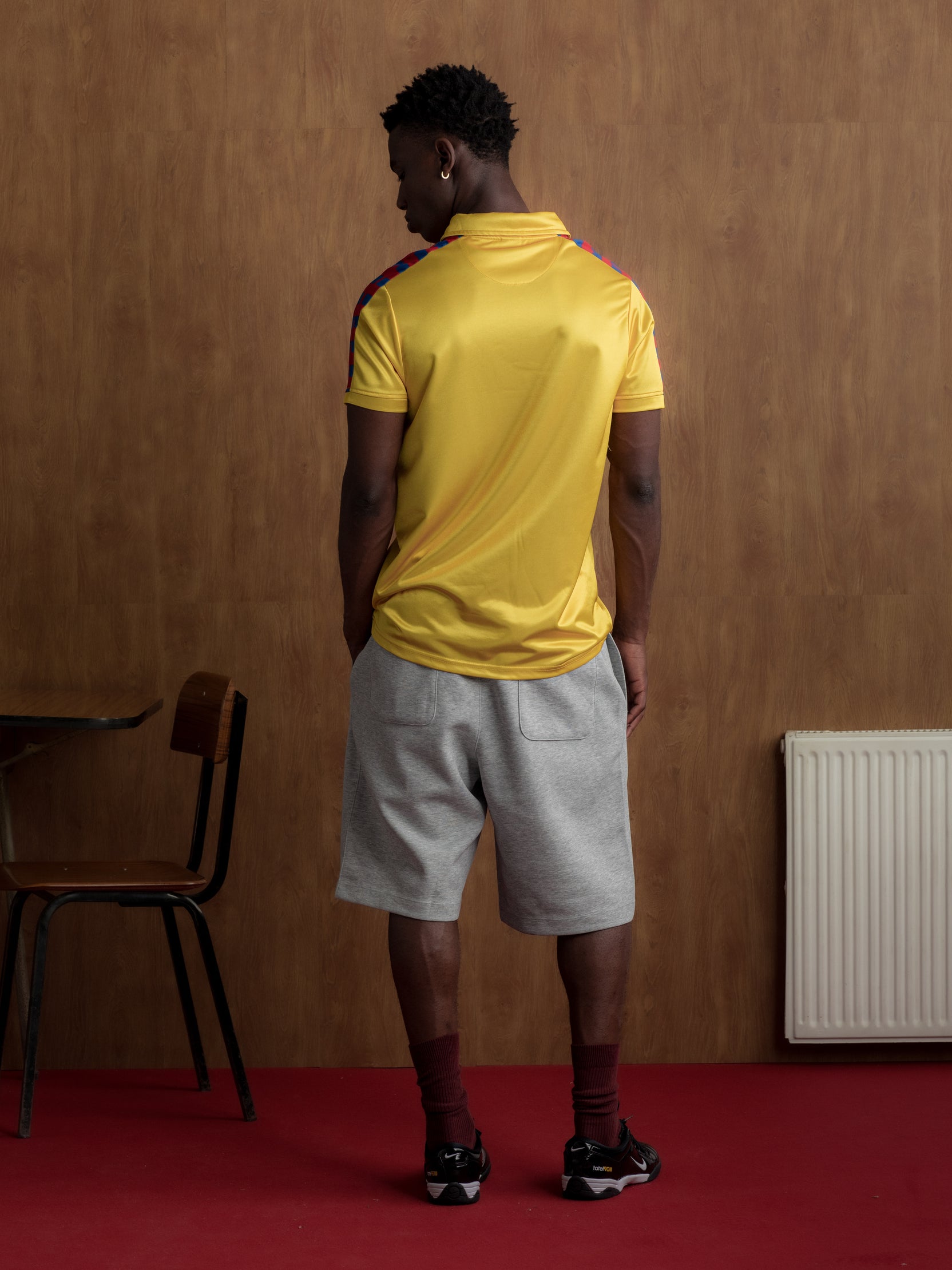 Yellow short-sleeve polo shirt with FC Barcelona crest and vertical red and blue stripe design.