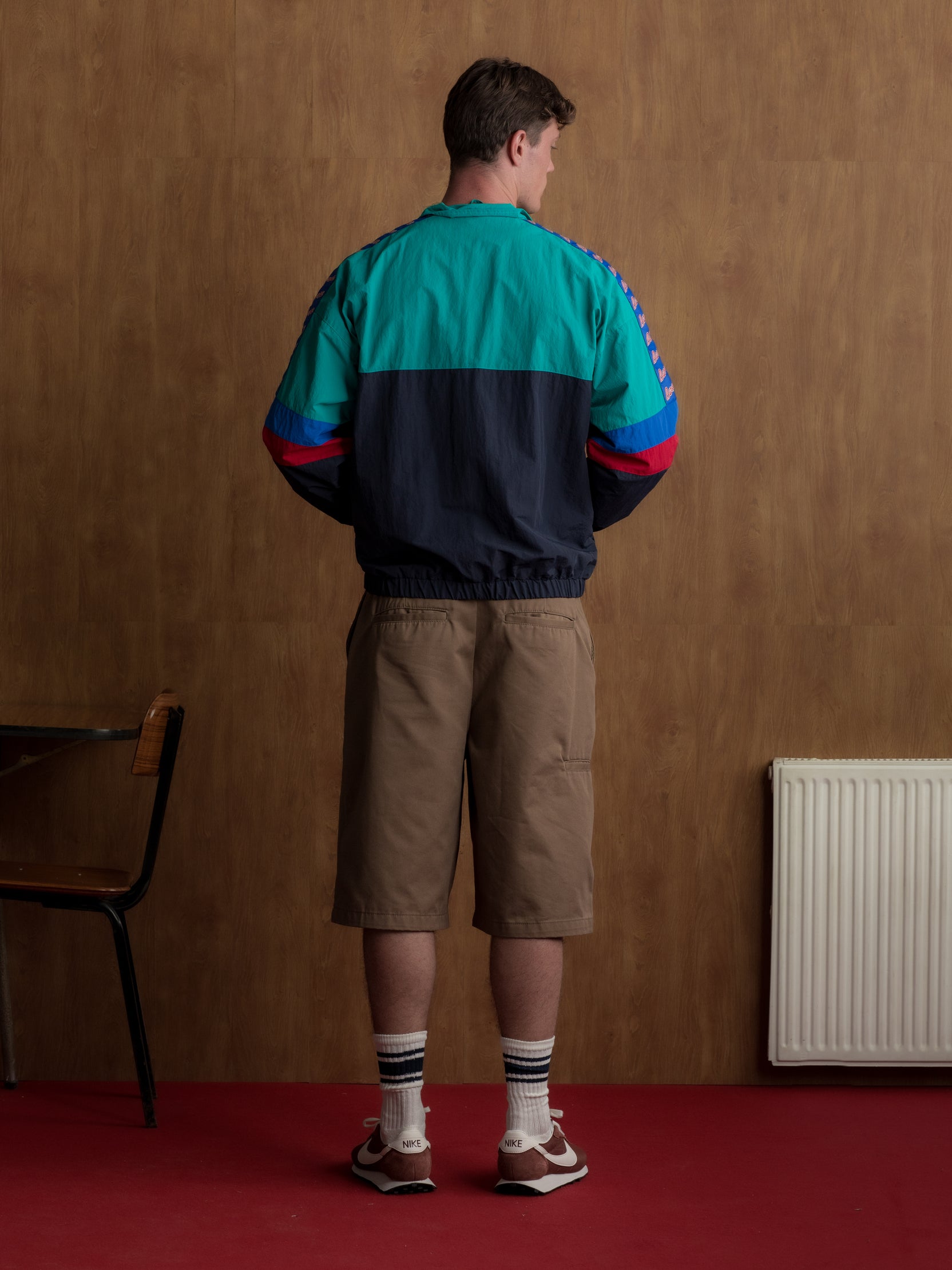 Retro-style windbreaker in teal, red, blue, and navy with FC Barcelona crest and embroidered 'Barça' text on the chest.
