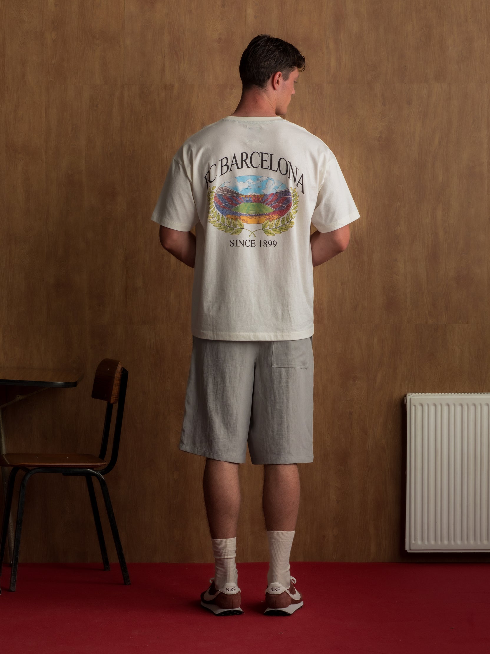 Cream T-shirt with large FC Barcelona stadium graphic, laurel wreath design, and 'FC Barcelona Since 1899' text on the back
