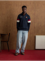 Man wearing a navy half-zip pullover with the FC Barcelona crest and '1899 Barça' text on the chest, featuring red and white stripes on the sleeves