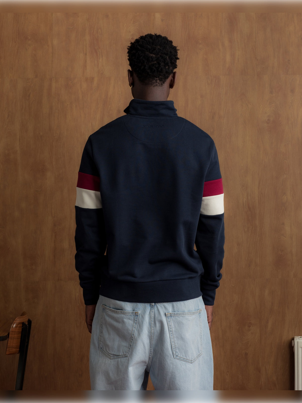 Man wearing a navy half-zip pullover with the FC Barcelona crest and '1899 Barça' text on the chest, featuring red and white stripes on the sleeves