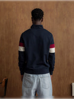 Man wearing a navy half-zip pullover with the FC Barcelona crest and '1899 Barça' text on the chest, featuring red and white stripes on the sleeves