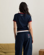 Model wearing a navy blue FC Barcelona T-shirt with red trim and club crest, paired with matching navy cargo pants featuring embroidered crest