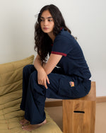 Model wearing a navy blue FC Barcelona T-shirt with red trim and club crest, paired with matching navy cargo pants featuring embroidered crest