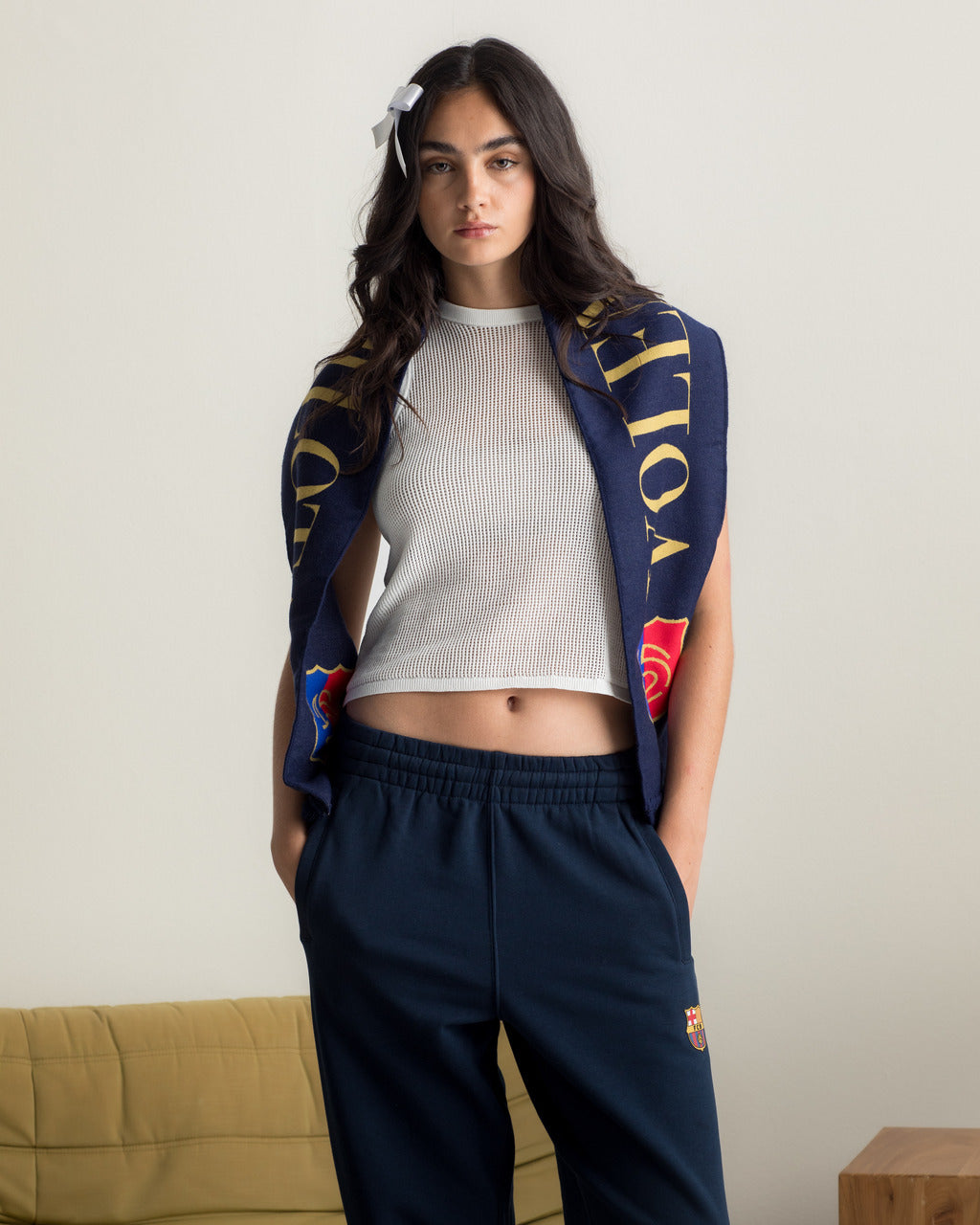 Model wearing navy blue FC Barcelona sweatpants with embroidered crest, paired with a white crop top and a navy scarf with gold lettering