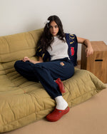 Model wearing navy blue FC Barcelona sweatpants with embroidered crest, paired with a white crop top and a navy scarf with gold lettering
