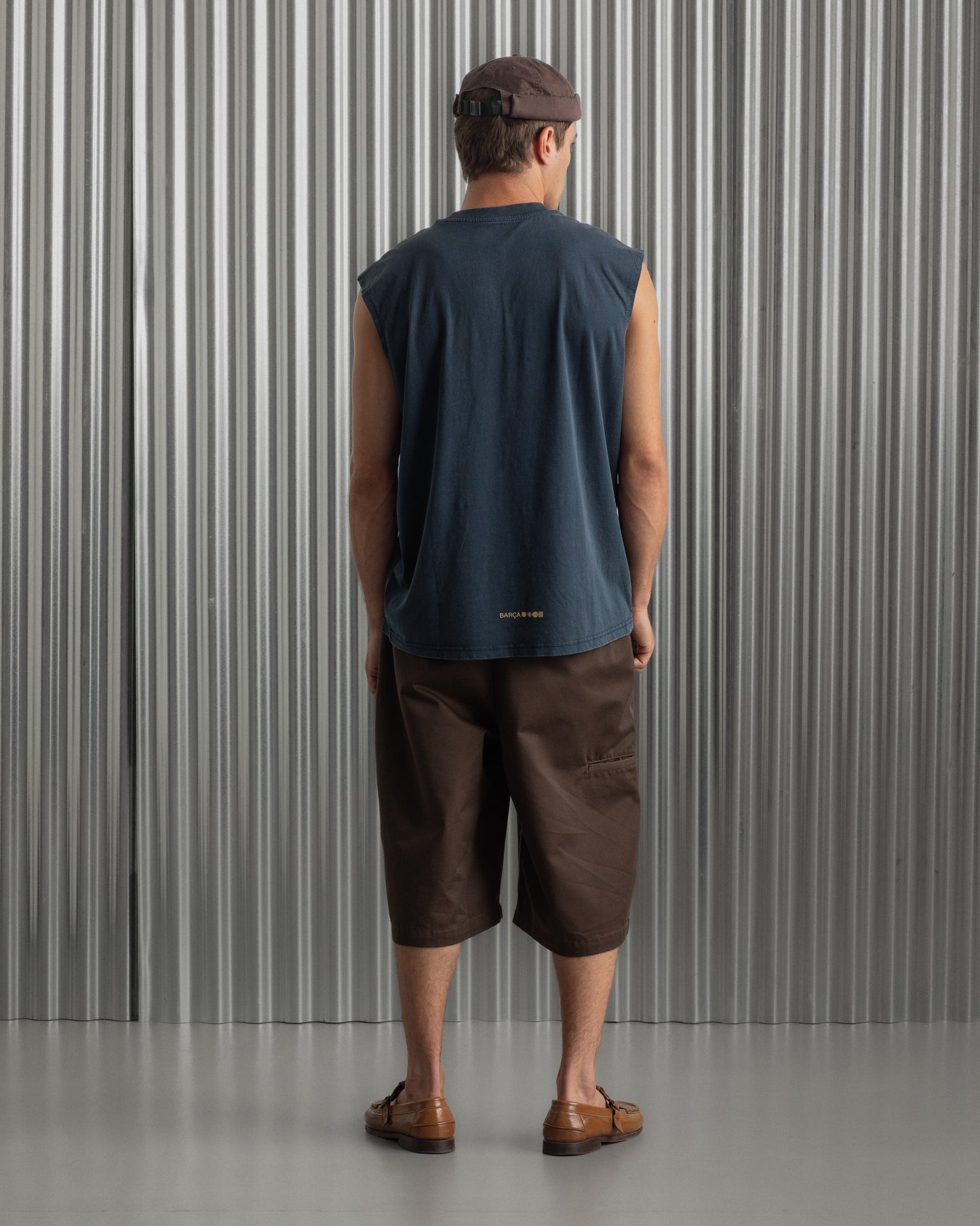 sleeveless navy blue FC Barcelona t-shirt with a small circular crest and text detail on the chest, paired with dark pants.