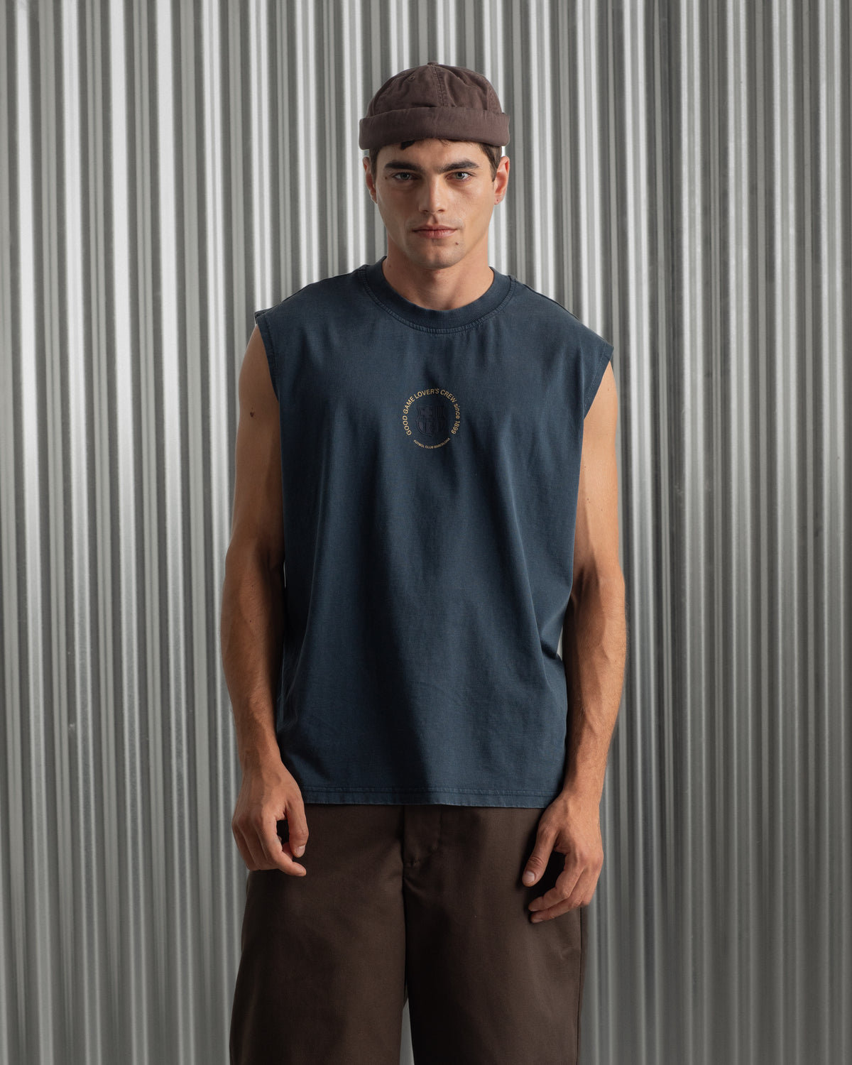 sleeveless navy blue FC Barcelona t-shirt with a small circular crest and text detail on the chest, paired with dark pants.