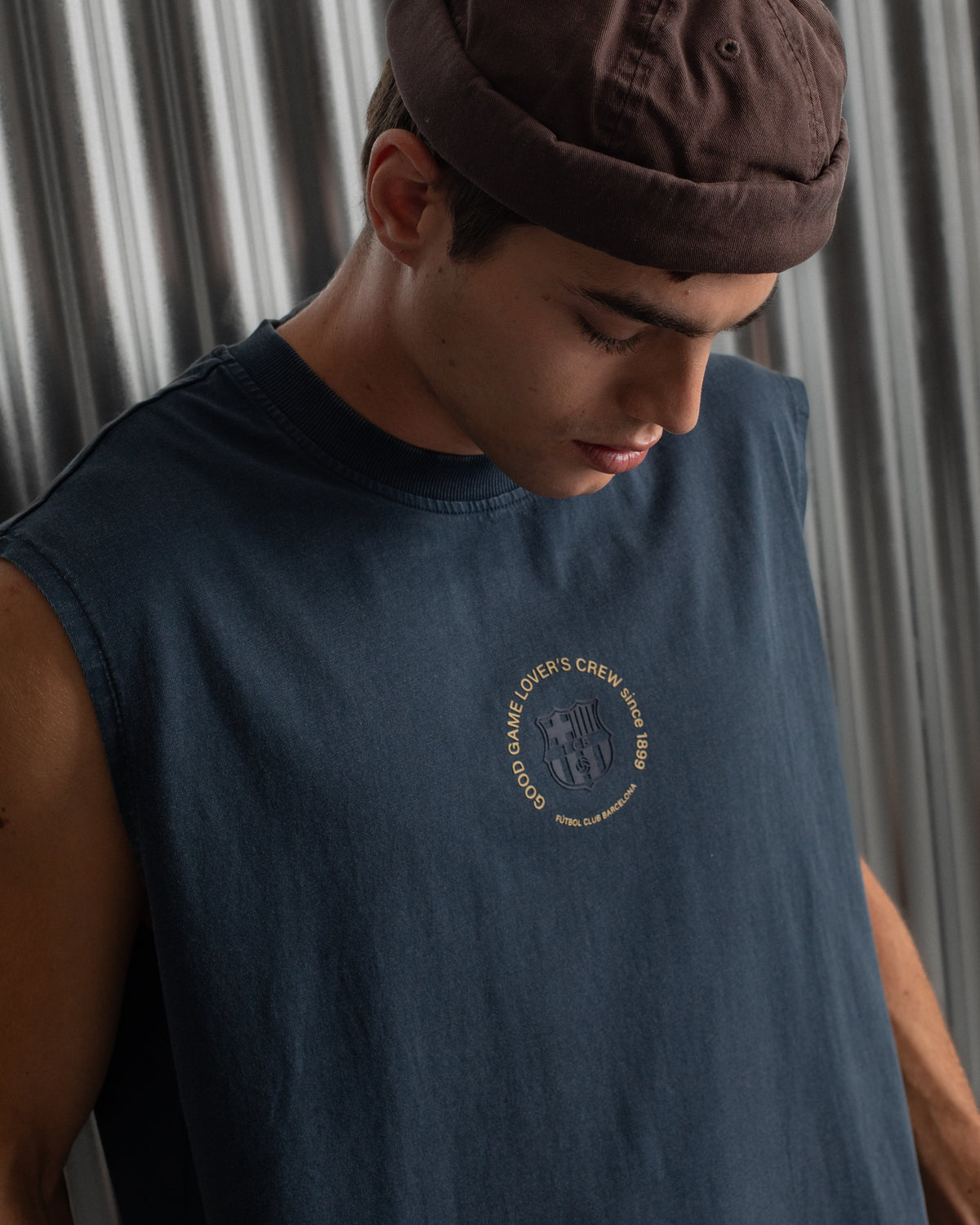 sleeveless navy blue FC Barcelona t-shirt with a small circular crest and text detail on the chest, paired with dark pants.