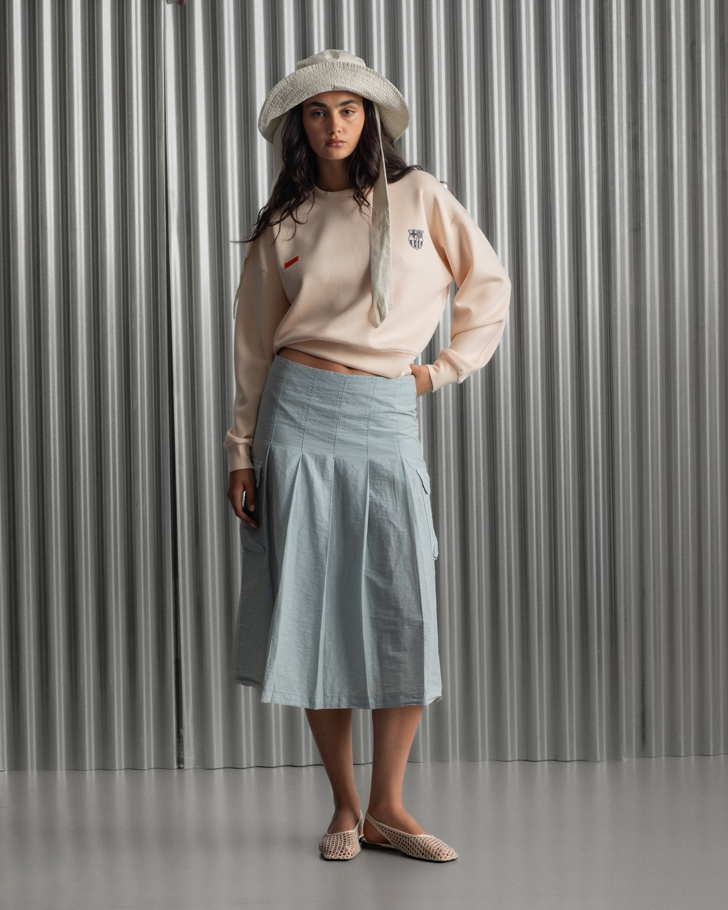 Light pink FC Barcelona sweatshirt with navy club crest on the chest and a small red rectangular detail on the left side.