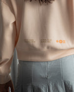 Light pink FC Barcelona sweatshirt with navy club crest on the chest and a small red rectangular detail on the left side.