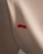 Light pink FC Barcelona sweatshirt with navy club crest on the chest and a small red rectangular detail on the left side.