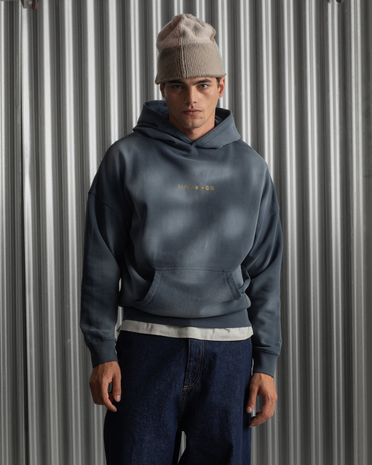 Man wearing a dark blue FC Barcelona hoodie with golden minimalist 'Barça' symbols printed on the chest