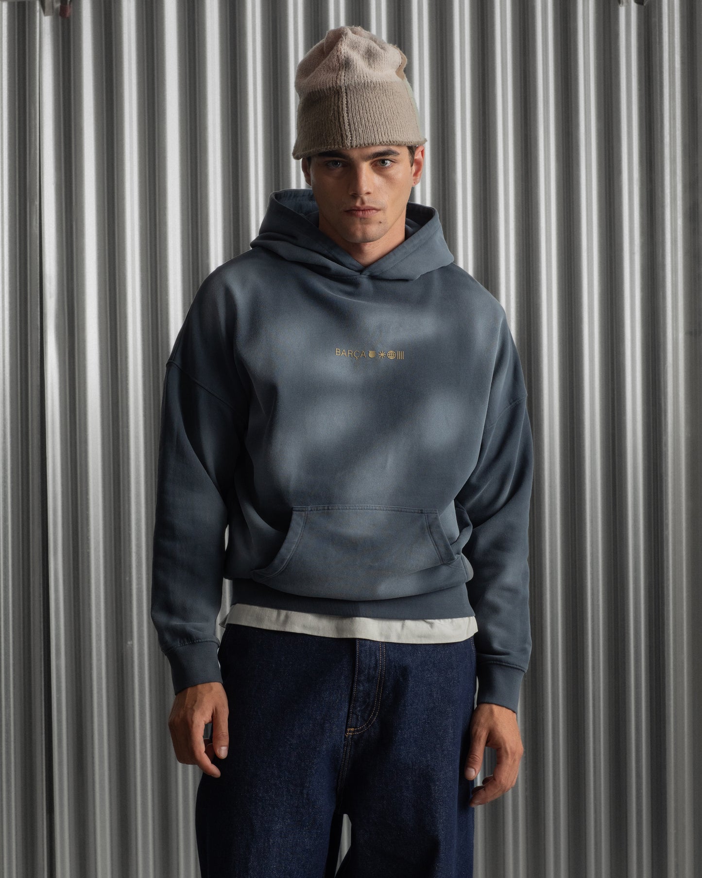 Man wearing a dark blue FC Barcelona hoodie with golden minimalist 'Barça' symbols printed on the chest