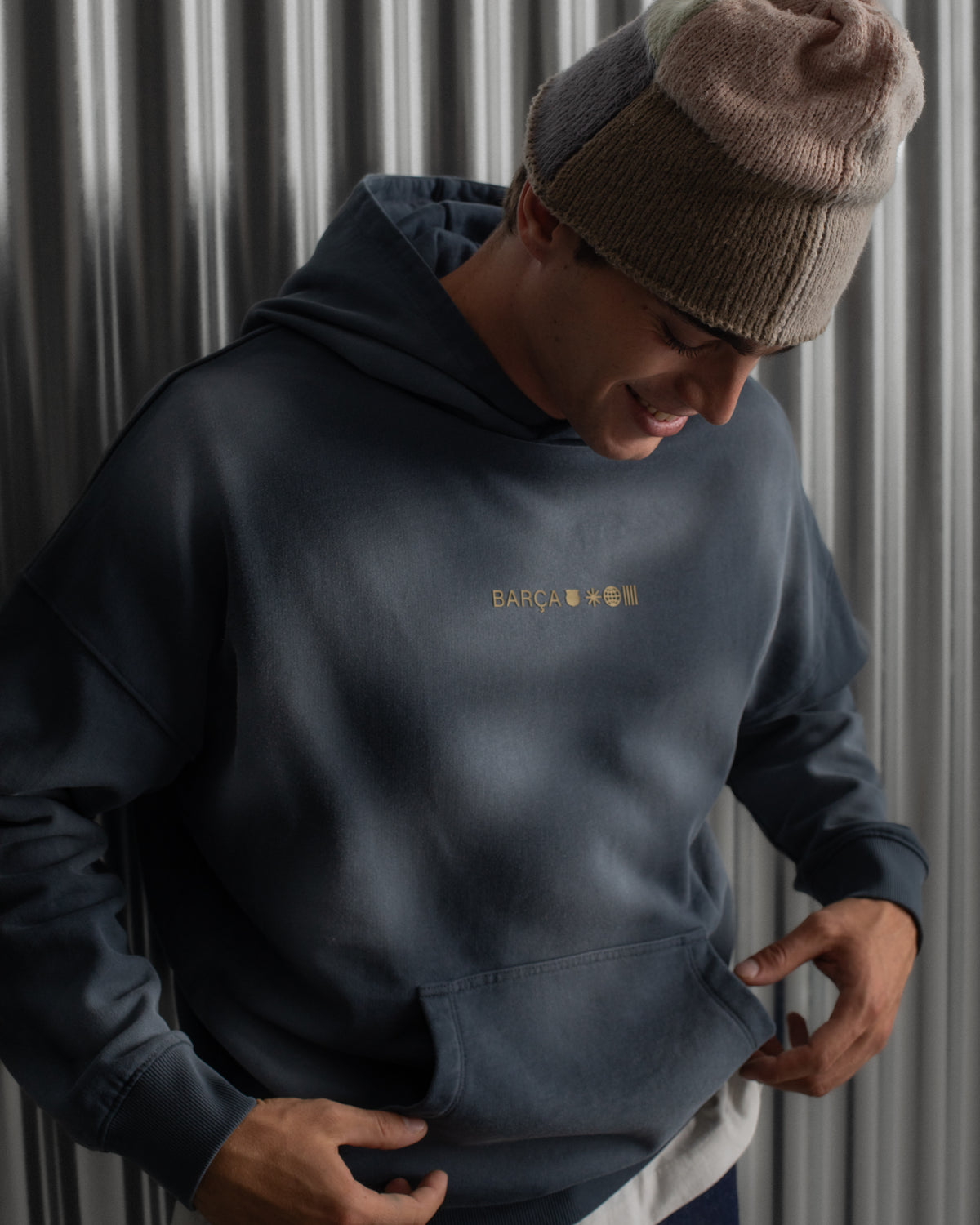 Man wearing a dark blue FC Barcelona hoodie with golden minimalist 'Barça' symbols printed on the chest
