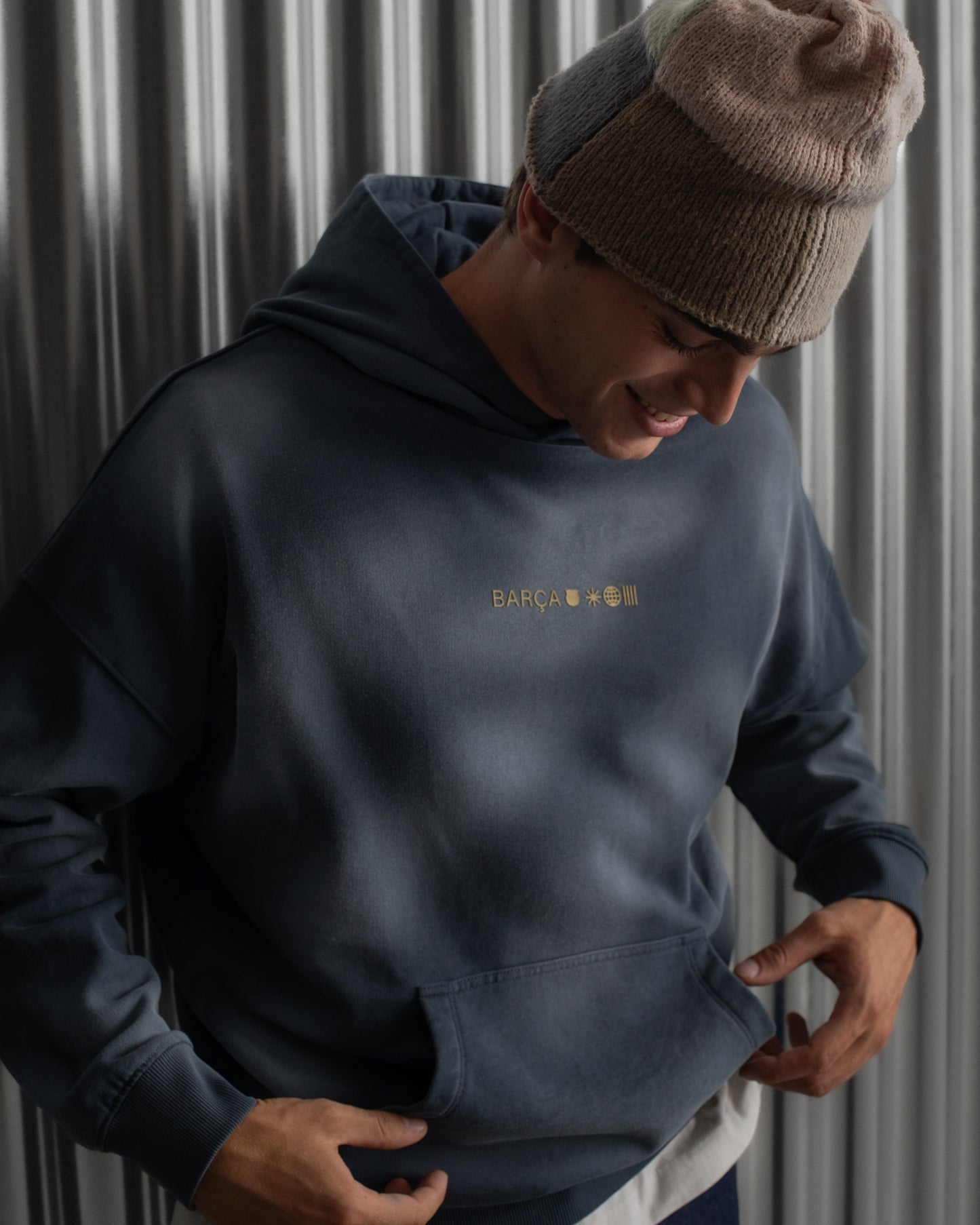 Man wearing a dark blue FC Barcelona hoodie with golden minimalist 'Barça' symbols printed on the chest