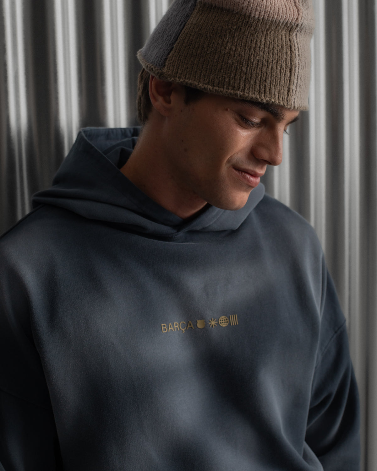 Man wearing a dark blue FC Barcelona hoodie with golden minimalist 'Barça' symbols printed on the chest