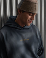 Man wearing a dark blue FC Barcelona hoodie with golden minimalist 'Barça' symbols printed on the chest