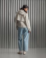 Chaqueta corta beige con capucha del FC Barcelona, cresta bordada en el pecho y detalles gráficos en rojo y dorado, combinada con pantalón vaquero azul claro