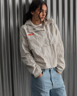 Chaqueta corta beige con capucha del FC Barcelona, cresta bordada en el pecho y detalles gráficos en rojo y dorado, combinada con pantalón vaquero azul claro