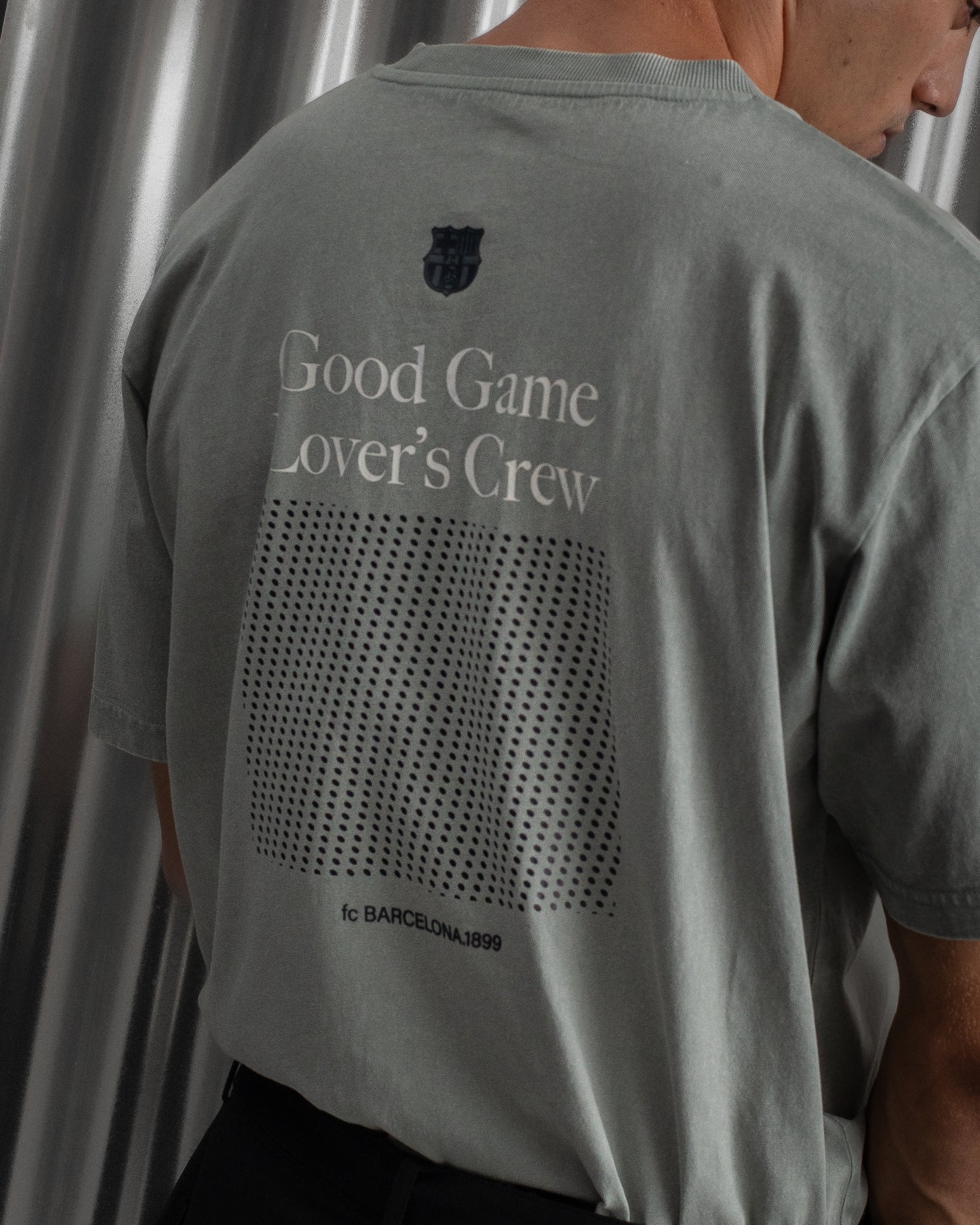 gray FC Barcelona t-shirt featuring the club crest, the text "Good Game Lover’s Crew," a dotted square graphic, and "fc BARCELONA 1899" printed at the bottom.