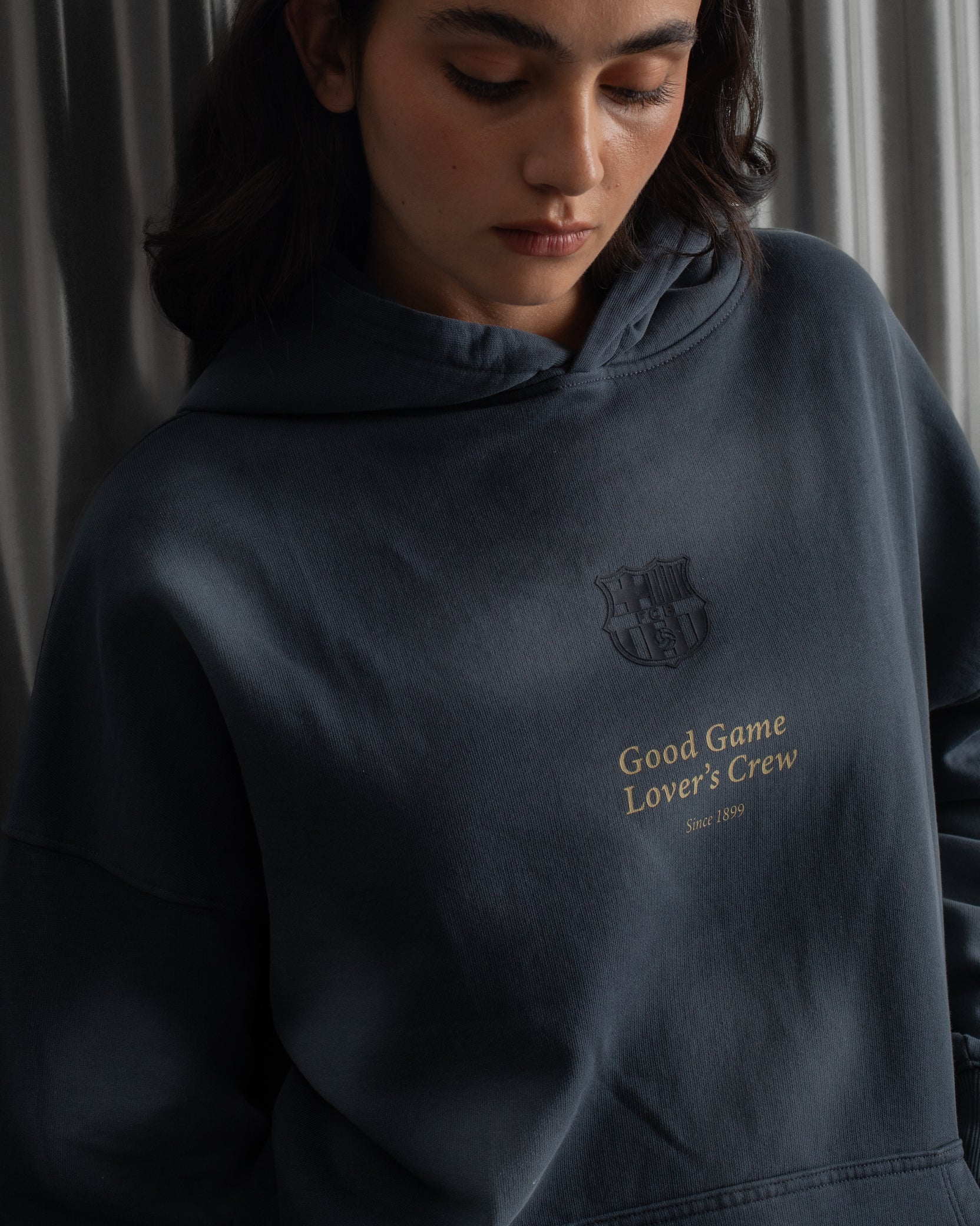 Dark blue FC Barcelona hoodie featuring the club crest and the phrase 'Good Game Lover’s Crew' embroidered on the front.