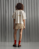 Beige cropped FC Barcelona t-shirt, back view, with gold FCB logo and the phrase “Good Game Lover’s Crew since 1899” printed in black above it.