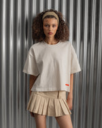 Beige cropped FC Barcelona t-shirt, back view, with gold FCB logo and the phrase “Good Game Lover’s Crew since 1899” printed in black above it.