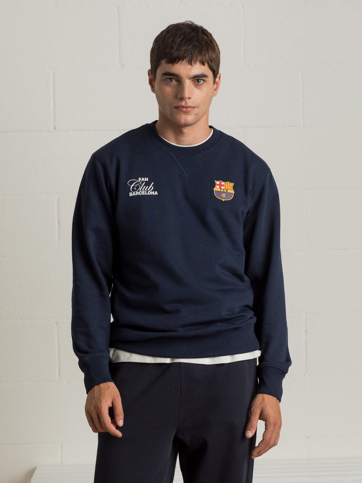 Man wearing a navy sweatshirt with a colorful abstract Barça design and 'Futbol Club Barcelona' text on the back