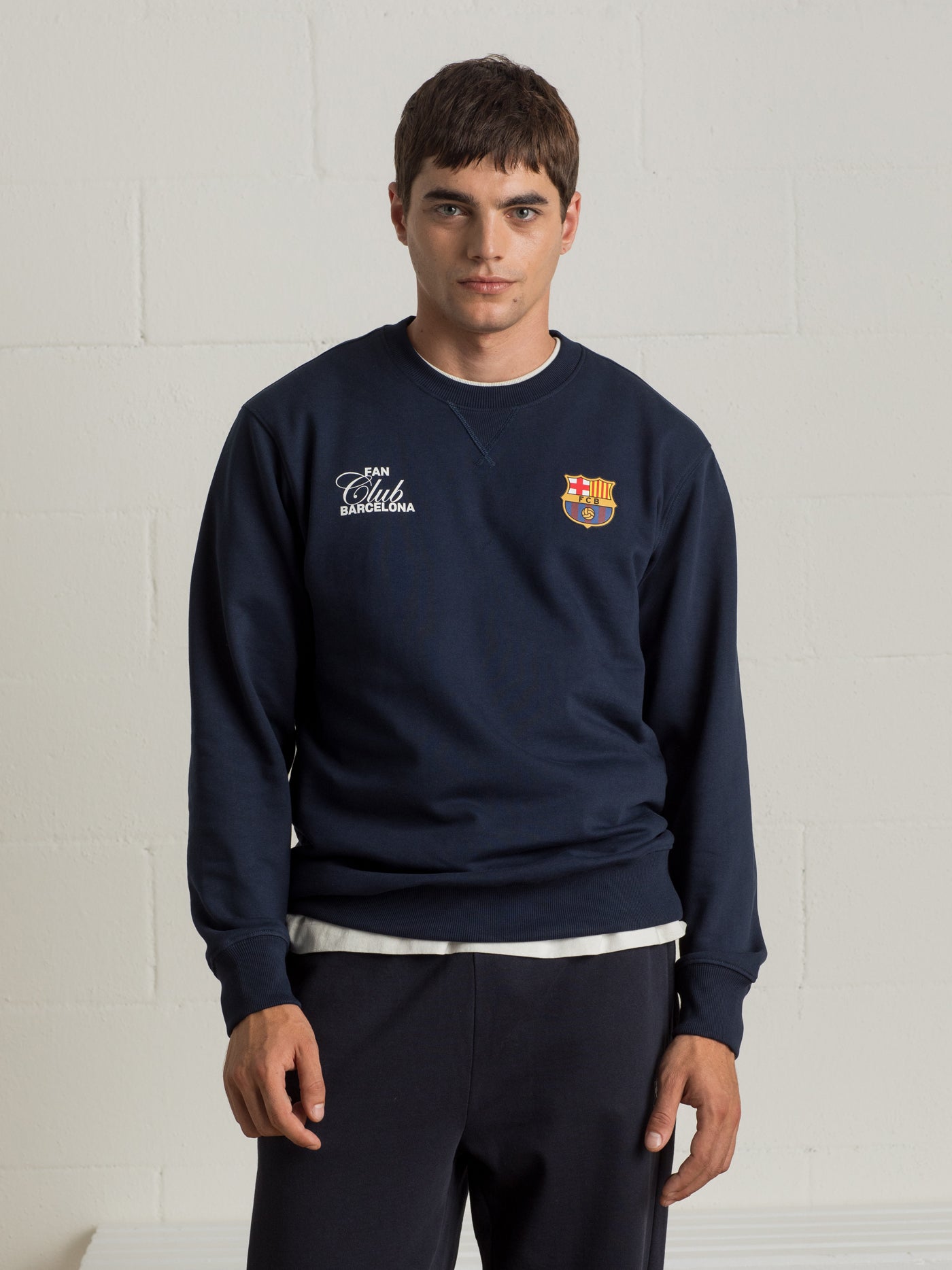 Man wearing a navy sweatshirt with a colorful abstract Barça design and 'Futbol Club Barcelona' text on the back