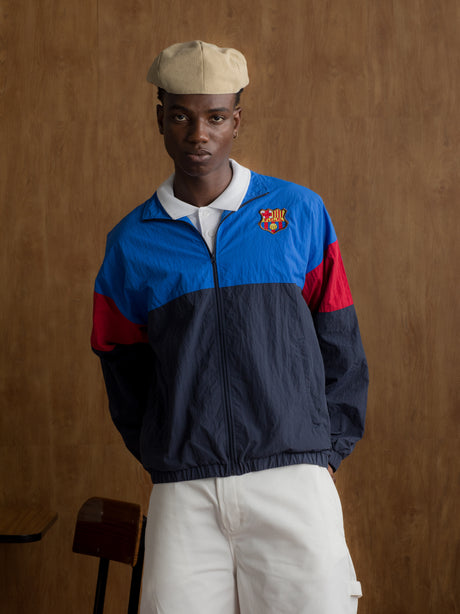 Color-block windbreaker in blue, red, and navy with FC Barcelona crest on the chest.
