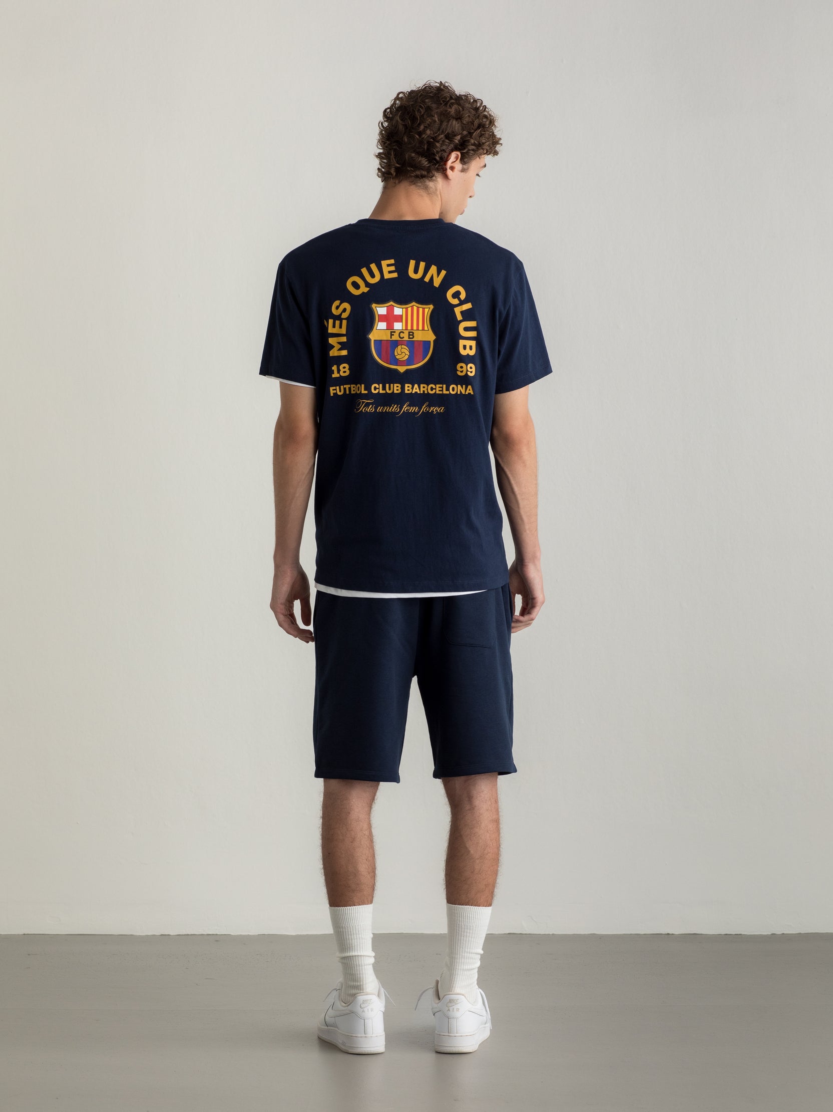 Navy T-shirt with FC Barcelona crest and 'Més que un club' slogan printed on the back.