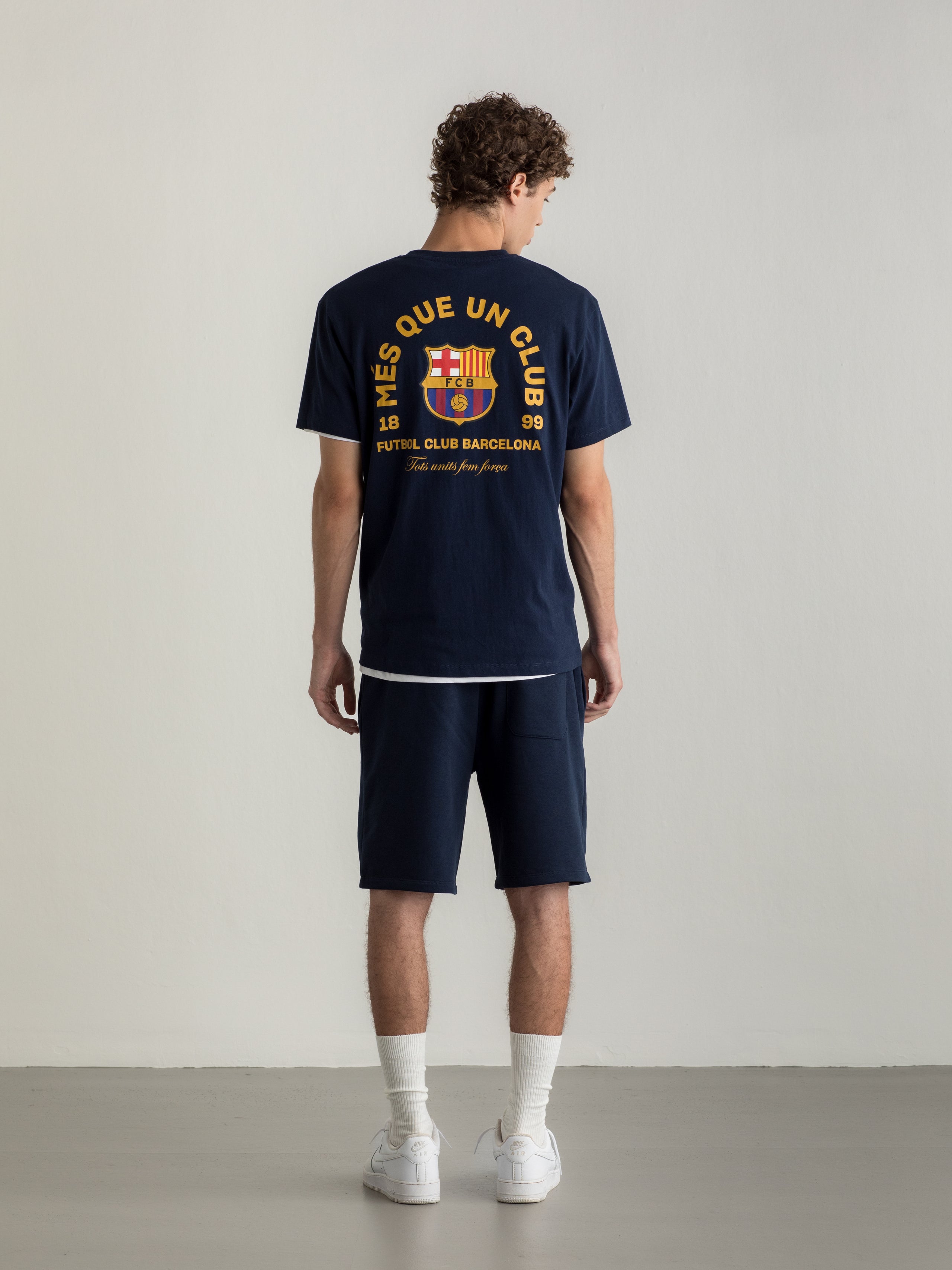 Navy T-shirt with FC Barcelona crest and 'Més que un club' slogan printed on the back.