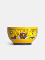 Vista frontal de un bol amarillo de FC Barcelona con gráficos de un gato de dibujos animados en los laterales y base azul oscuro.
