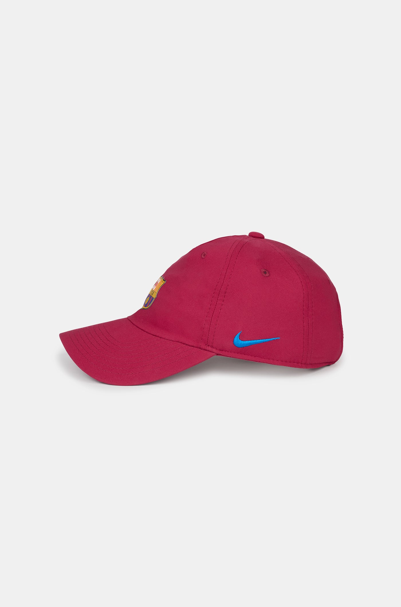 Red curved-brim cap featuring the FC Barcelona crest on the front and a blue Nike swoosh embroidered on the side.