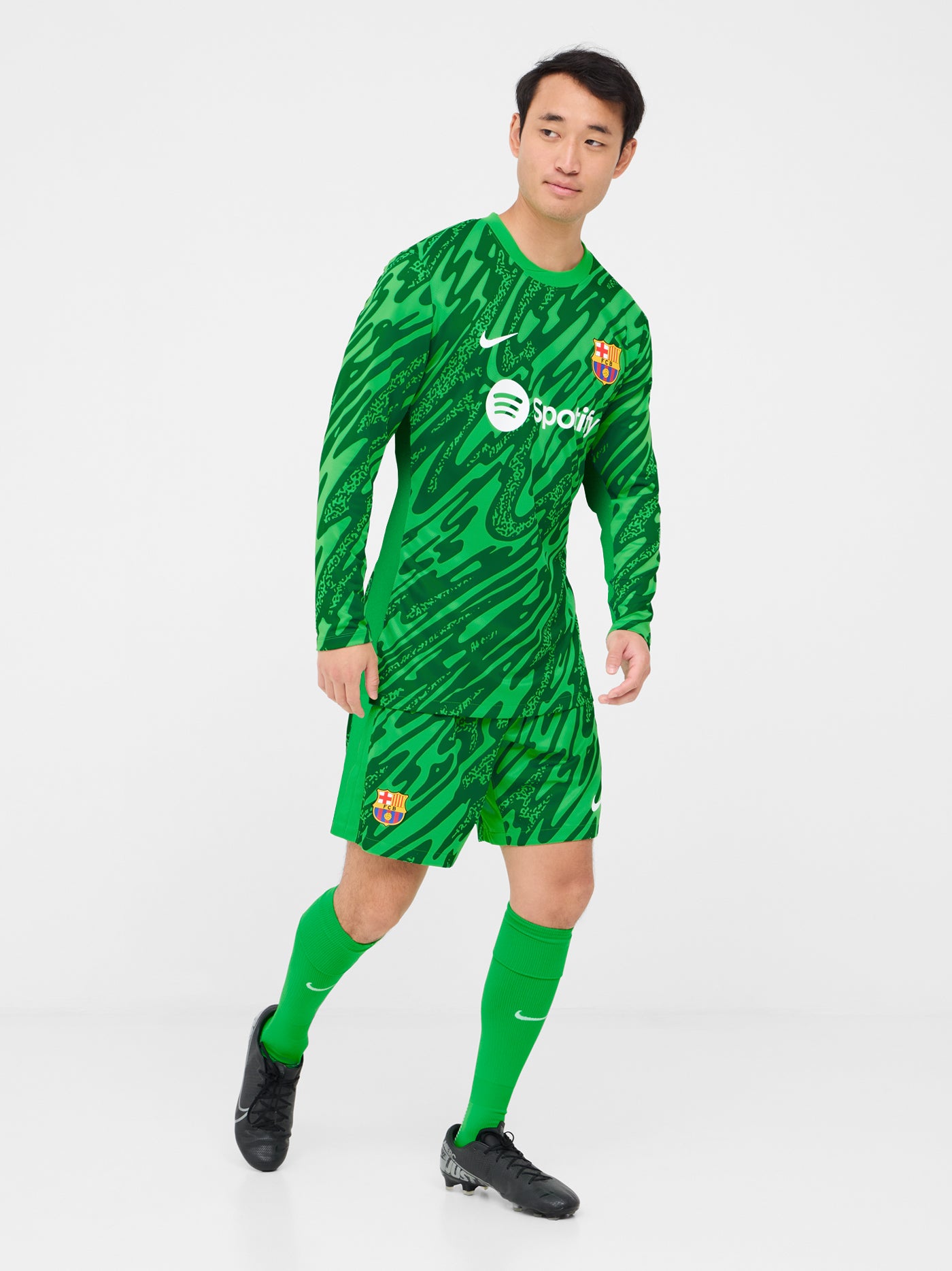 Person wearing green FC Barcelona goalkeeper shorts with abstract pattern, Nike logo, and club crest.


