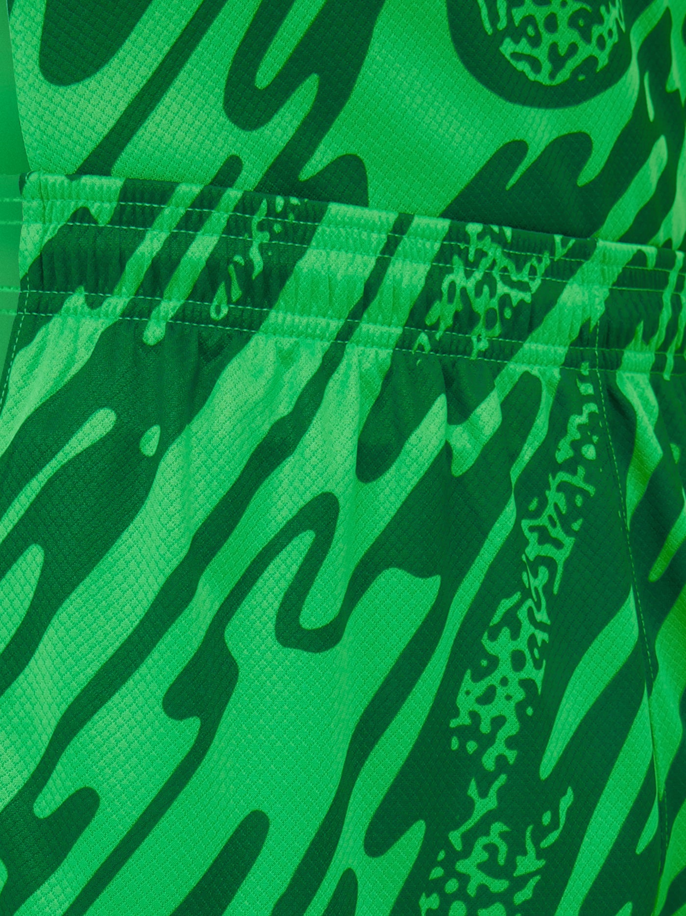 Person wearing green FC Barcelona goalkeeper shorts with abstract pattern, Nike logo, and club crest.