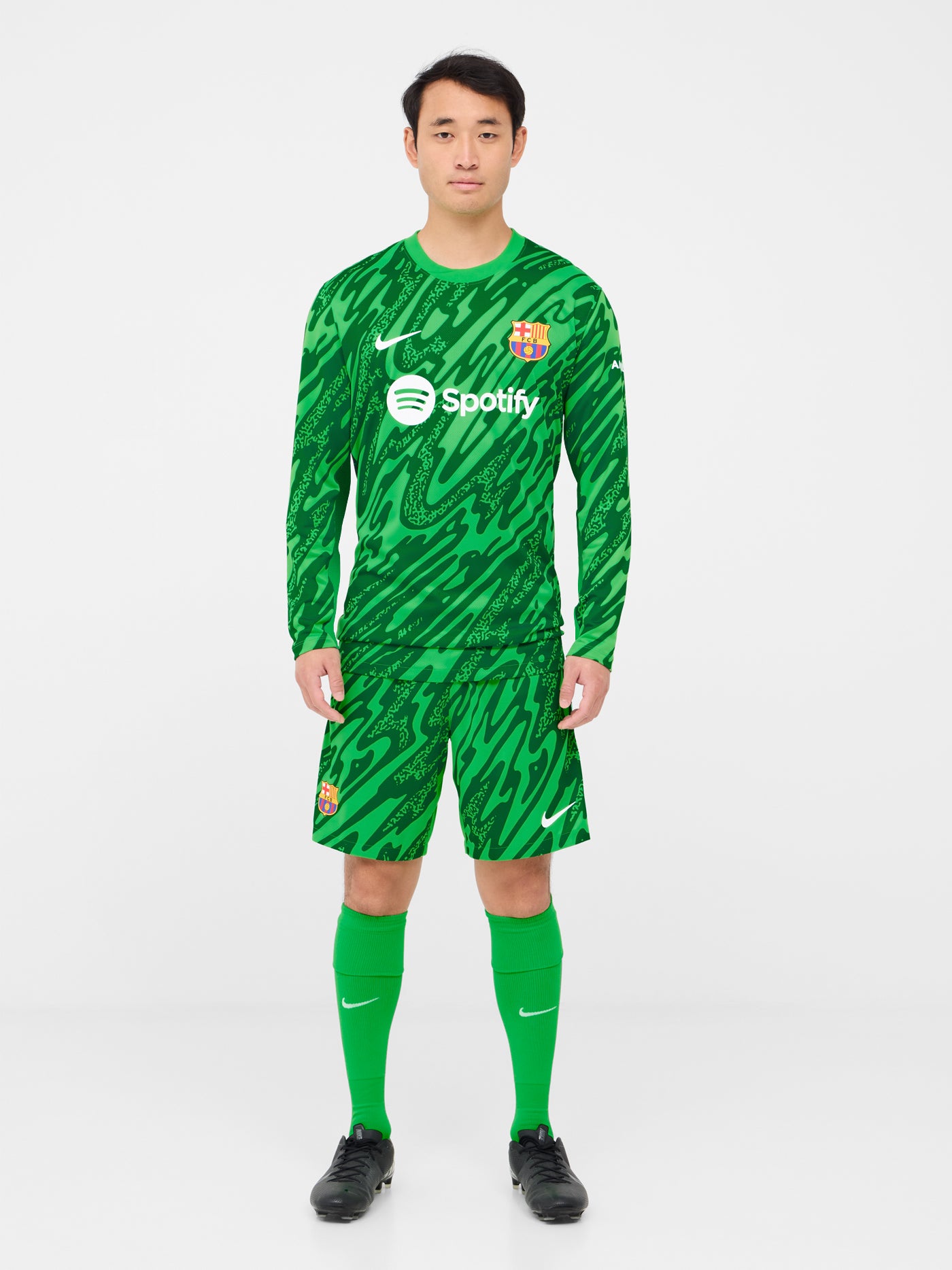 Person wearing green FC Barcelona goalkeeper shorts with abstract pattern, Nike logo, and club crest.