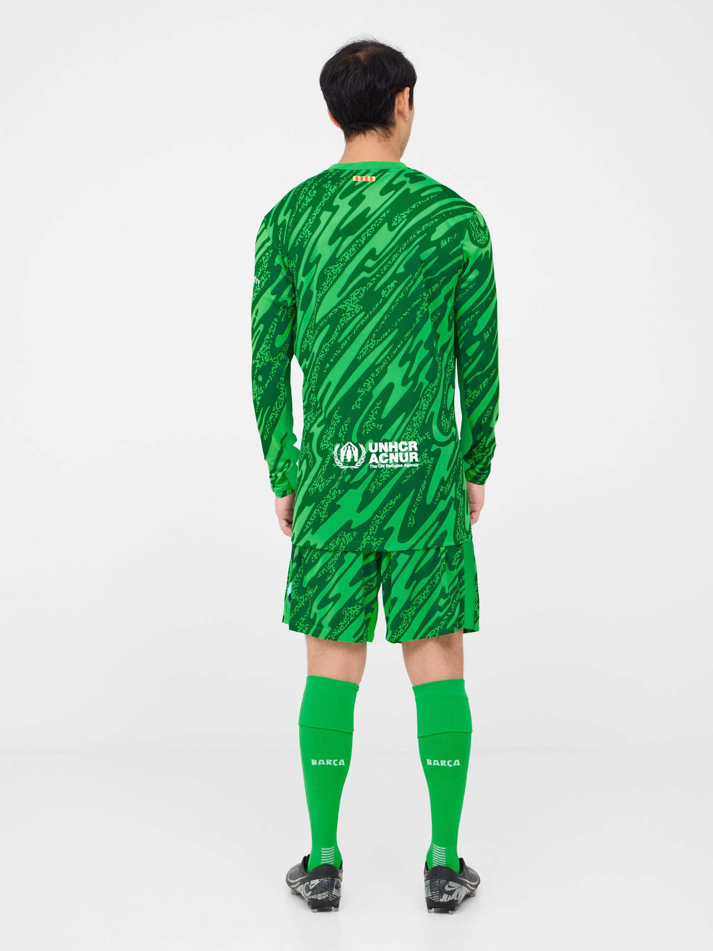 Person wearing green FC Barcelona goalkeeper shorts with abstract pattern, Nike logo, and club crest.