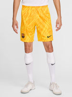 Person wearing bright yellow FC Barcelona goalkeeper shorts with abstract pattern, Nike logo, and club crest.


