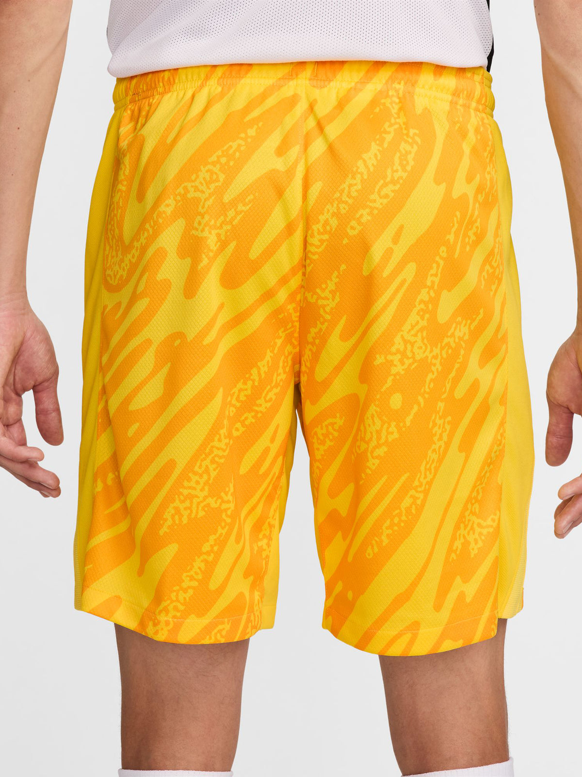 Person wearing bright yellow FC Barcelona goalkeeper shorts with abstract pattern, Nike logo, and club crest.