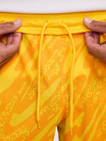 Person wearing bright yellow FC Barcelona goalkeeper shorts with abstract pattern, Nike logo, and club crest.