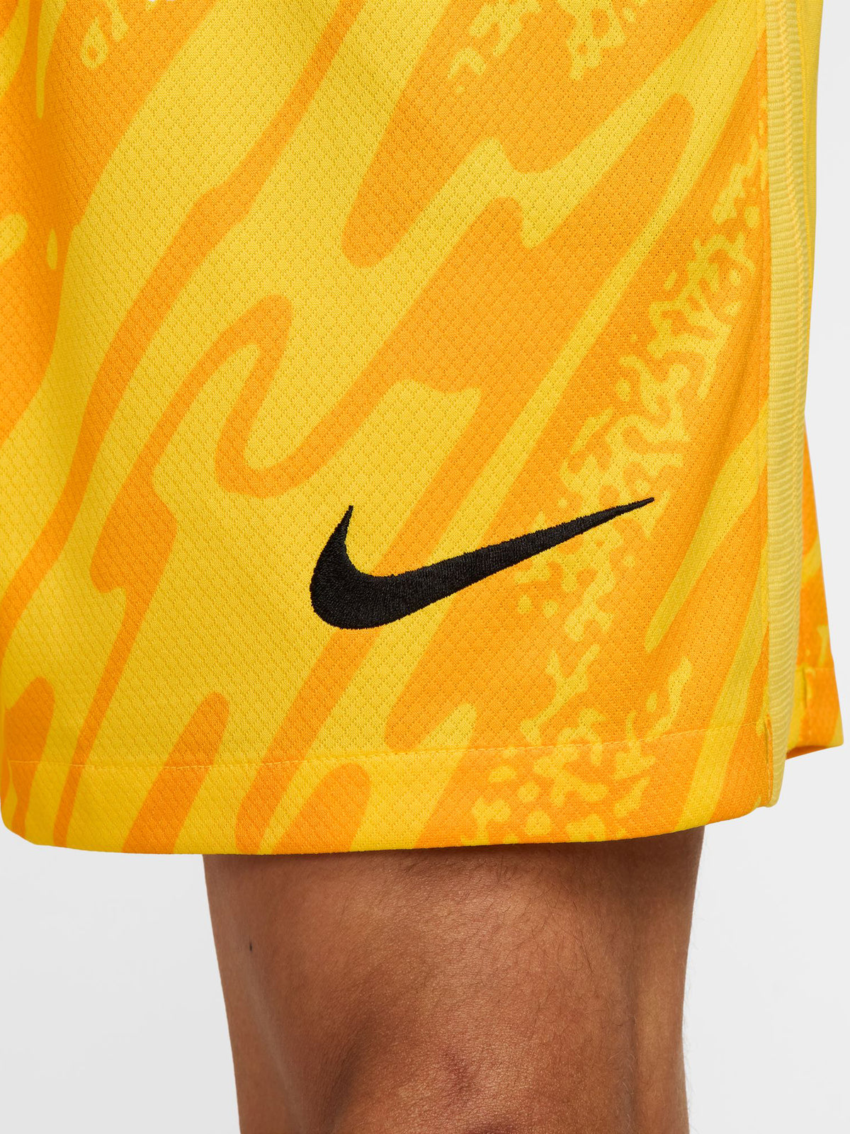 Person wearing bright yellow FC Barcelona goalkeeper shorts with abstract pattern, Nike logo, and club crest.