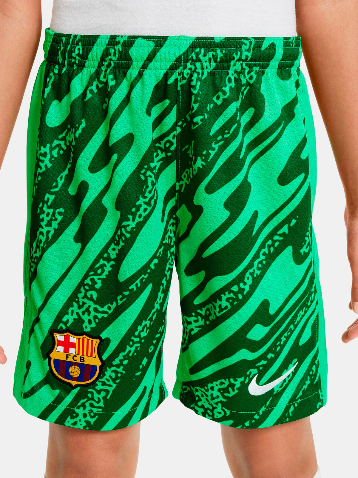 Person wearing green FC Barcelona goalkeeper shorts with abstract pattern, Nike logo, and club crest.
