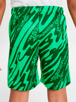 Person wearing green FC Barcelona goalkeeper shorts with abstract pattern, Nike logo, and club crest.