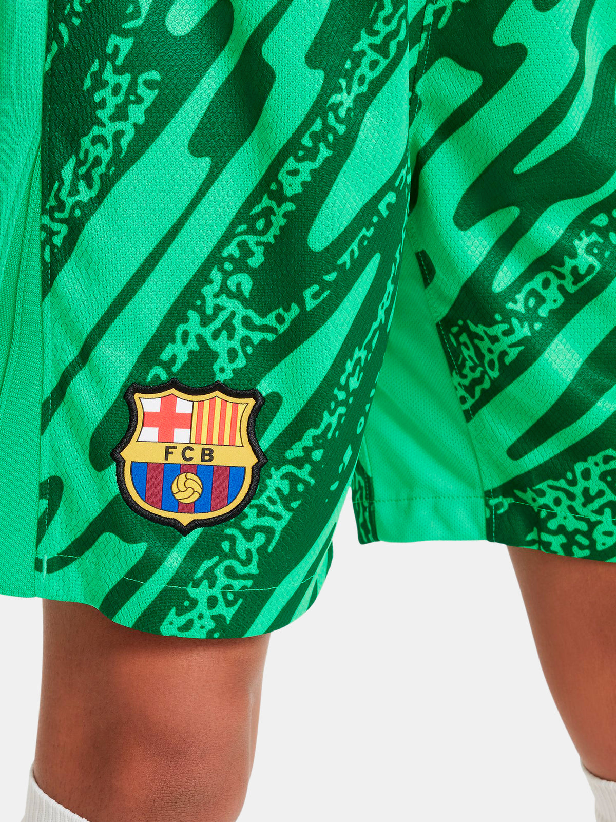 Person wearing green FC Barcelona goalkeeper shorts with abstract pattern, Nike logo, and club crest.