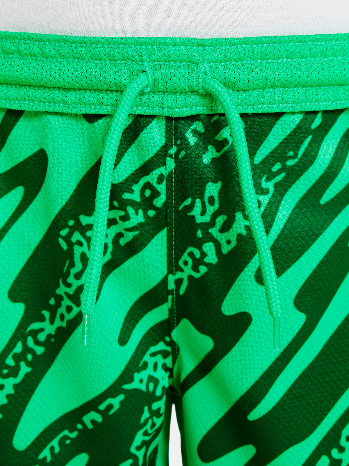 Person wearing green FC Barcelona goalkeeper shorts with abstract pattern, Nike logo, and club crest.