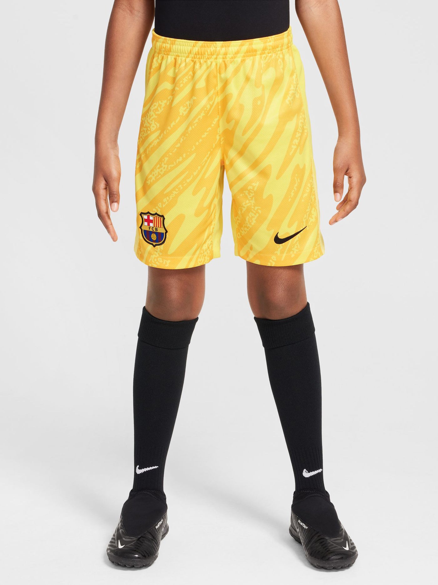 Person wearing bright yellow FC Barcelona goalkeeper shorts with abstract pattern, Nike logo, and club crest.


